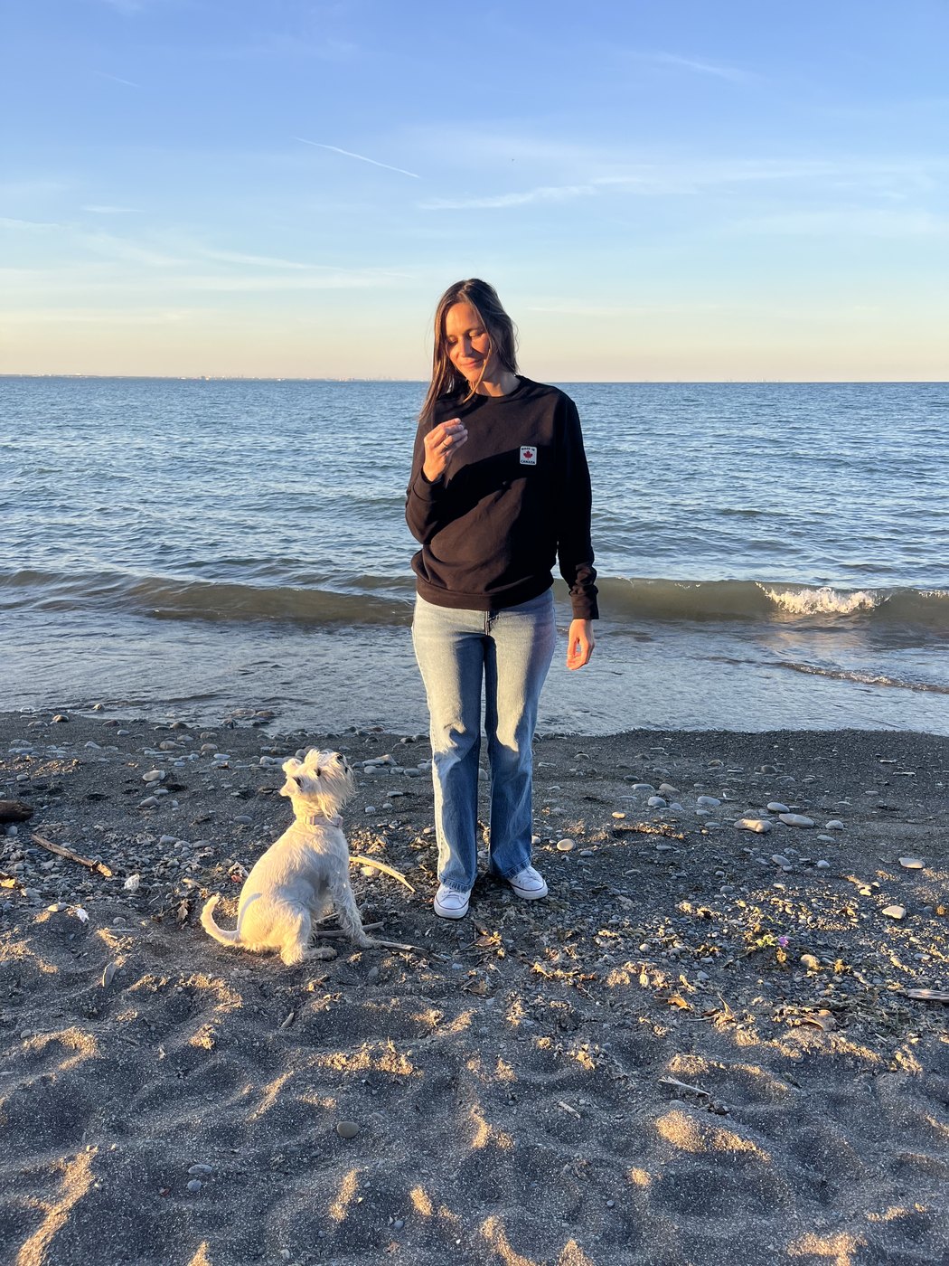 Maria Ostapenko at golden hour on a lakeshore beach with her dog